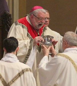 Bishop Jenky breathes over the opening of the vessel containing the sacred chrism as a sign of infusing it with the Holy Spirit. (The Catholic Post/Jennifer Willems)