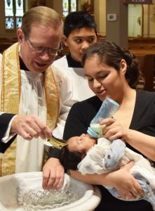 Msgr. Deptula baptizes Anthony, held by Maricela. (The Catholic Post/Tom Dermody)