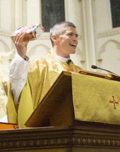 Father Anthony Co holds a gift-wrapped brick he presented to the oldest alumnus of Sacred Heart School attending Christmas Mass. (Provided photo)