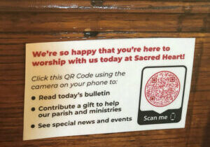A business card-sized welcome message including a QR code for scanning by smartphone cameras is seen on the back of a pew at Sacred Heart Church in Rock Island. (Provided photo)