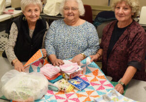 Pictured assembling a layette Nov. 15 for a needy family with a newborn are Christ Child of Central Illinois members, from left, Shari Paris of the Pontiac Circle, Pam Tomlianovich of the Peoria Circle; and Judy Weber, also of the Pontiac Circle. (The Catholic Post/Tom Dermody)