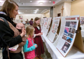 Kristen Kucner and daughters Lucia (asleep), Julia and Anna of Dunlap learn more about a eucharistic miracle from Poland, where the girls' grandfather is from. They visited the Vatican International Exhibition of "The Eucharistic Miracles of the World" on Nov. 19 at the Spalding Pastoral Center in Peoria. The Catholic Post/Jennifer Willems